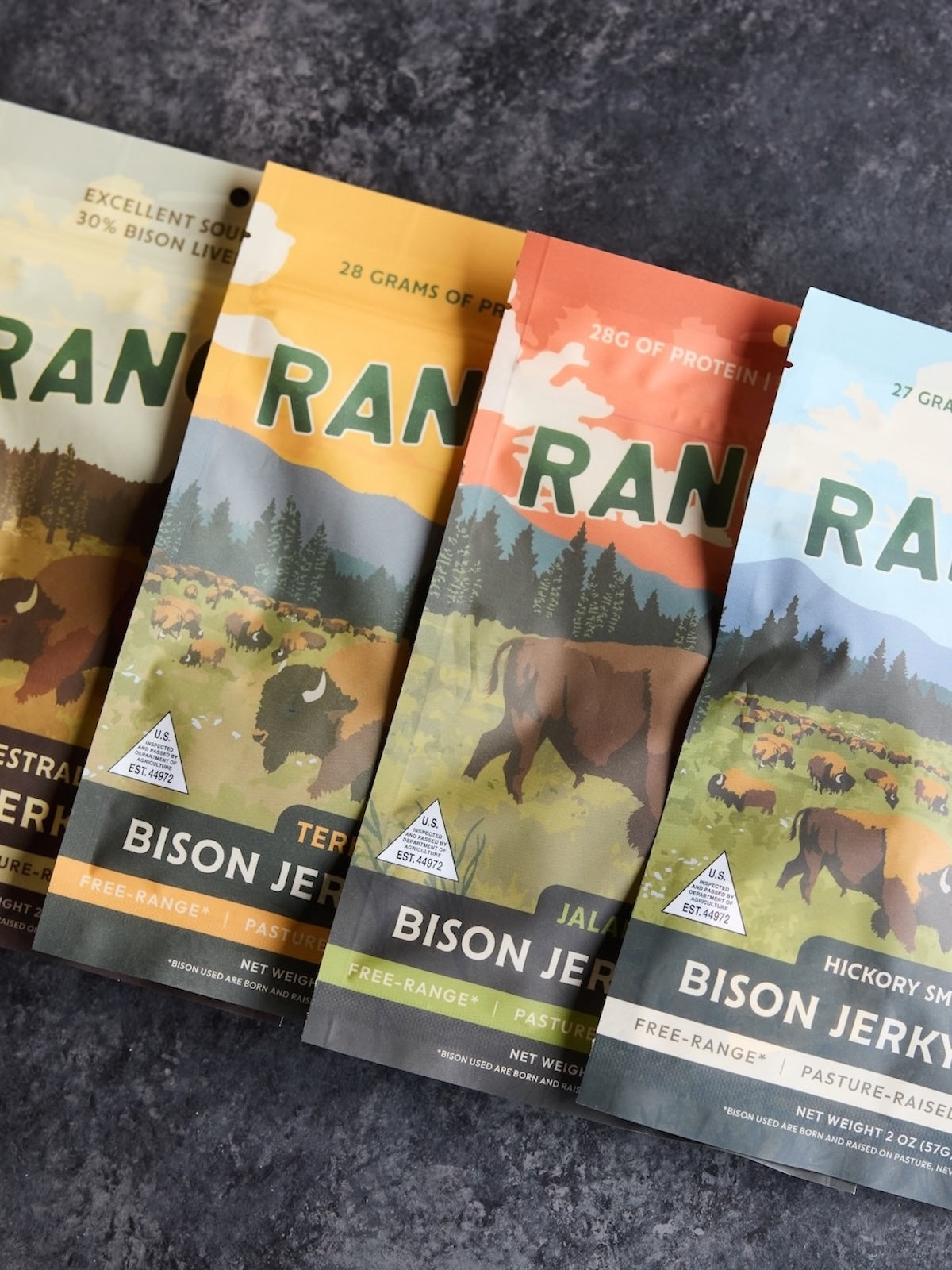 Four packages of Ran brand bison jerky on a dark surface